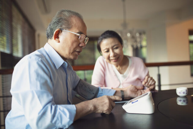 Man and woman sitting at a table checking blood pressure