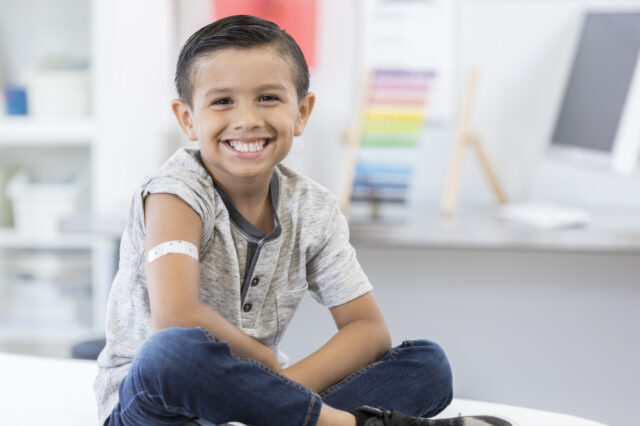 Child smiling with a band aid on his arm