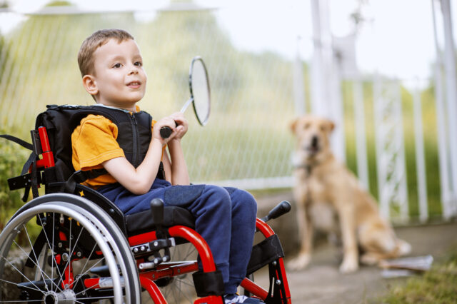 Child in a wheelchair holding a racket