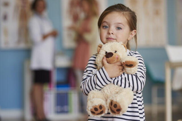 Child holding stuffed animal and looking at camera