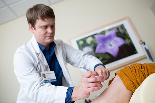 A healthcare professional inserts acupuncture needles.