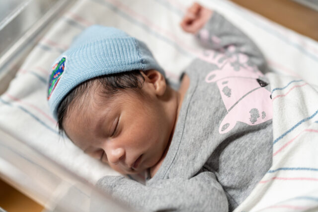 Newborn wearing UF Health beanie