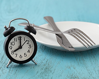 Stock image of an alarm clock next to a plate