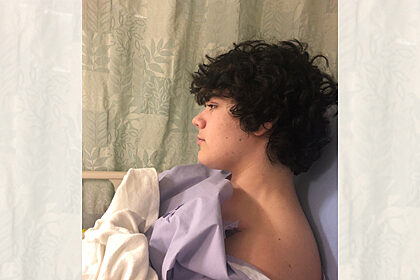 profile view of a teen boy in a hospital gown in a hospital bed