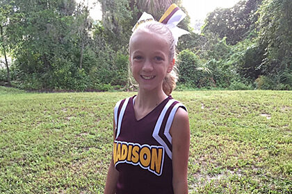 madison standing outside and smiling at the camera in a cheerleading uniform