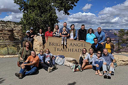 group of people around a sign that says bright angel trailhead