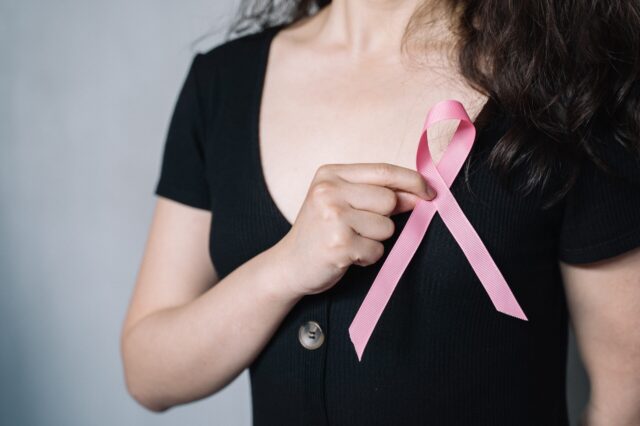 Woman holding breast cancer ribbon over her chest