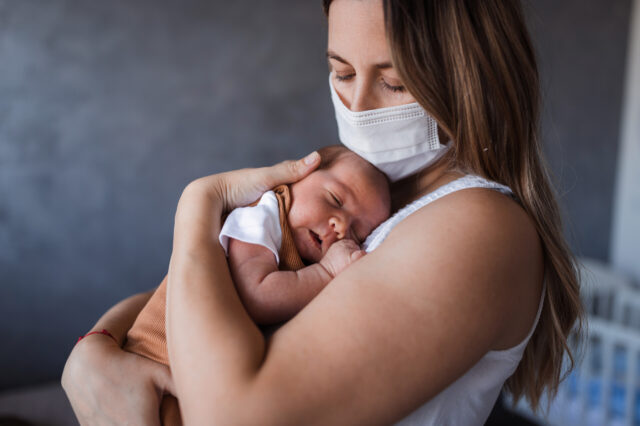 Mom wearing a mask and holding her baby
