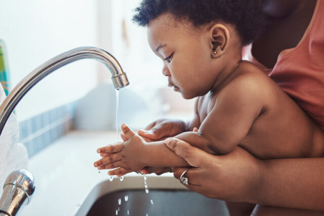 Parent helping baby wash hands