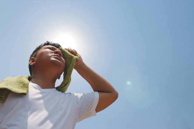 Person wiping their head with a towel and looking at the sun