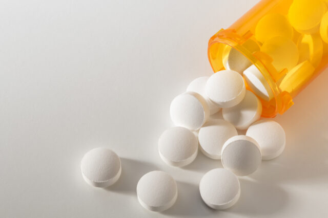 Stock image of white pills spilling from an amber pill bottle