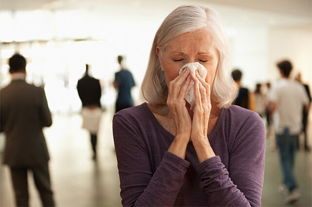 Woman sneezing in a crowded lobby.