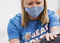 A female health care worker wearing a Beat Covid t-shirt with Gator colors administers a COVID vaccine.