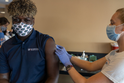 UF student John Hazzard receives a COVID-19 vaccination from Cynthia Guerin, a fourth-year UF College of Medicine student, at Ben Hill Griffin Stadium on Monday.
