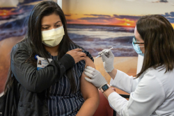 Admission specialist Emily Benitez receives the Moderna vaccine from pharmacist Suzy Wise, Pharm.D, at the UF Health Shands Cancer Hospital. (Photo by Louis Brems)
