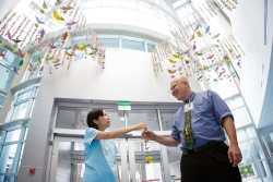 Kathy Liu, Joey’s mother, presents some of the hand-made cranes to William Slayton, M.D., division chief and program director of the pediatric hematology and oncology division at UF Health.