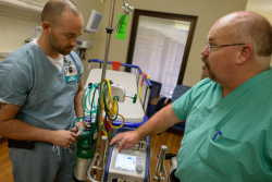 Tim Bantle, R.R.T., left, along with Jeff Brown, ECMO Specialist, examine a portable ECMO machine that enables critically ill patients to be more easily transported to UF Health Shands Hospital. Photo credit: Jesse Jones