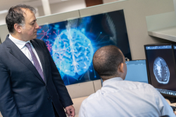 Reza Forghani, M.D., Ph.D., (left) a professor of radiology and AI, discusses images with Kevin Pierre, M.D., a clinical radiology fellow, in Forghani’s lab at the Norman Fixel Institute for Neurological Diseases.  