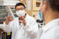 Andrew Liu, Ph.D., speaks to a colleague in his lab. (Photo by Jesse S. Jones)
