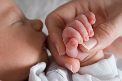 newborn baby holding onto his mother's thumb