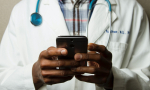 A physician holds a phone in his hand